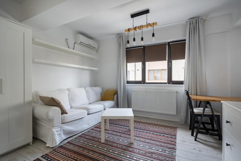 een woonkamer met een witte bank en een tafel bij Concept Studio Haven 19 in Boekarest