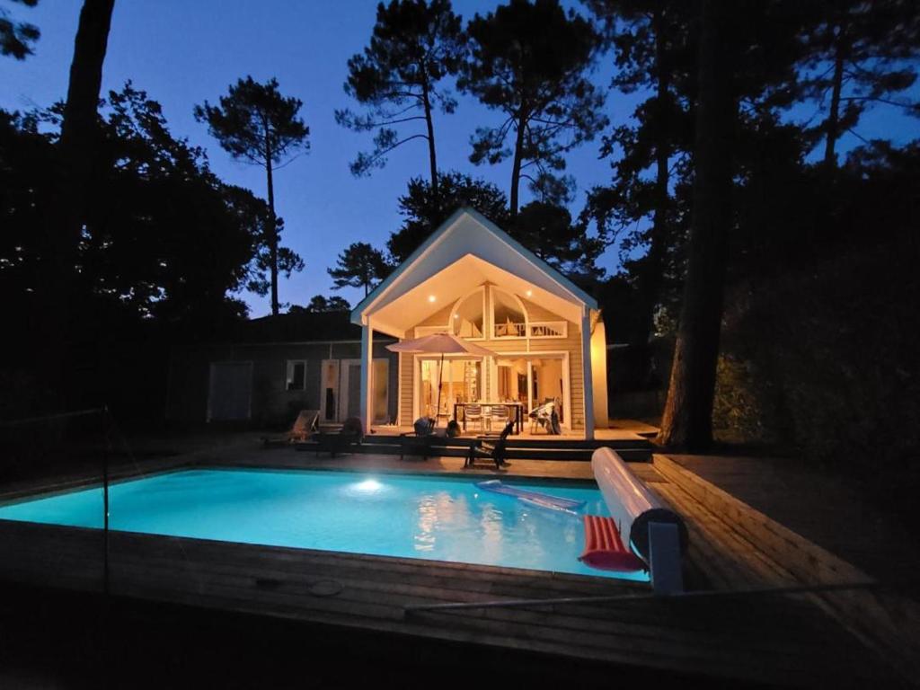 une petite maison avec une piscine la nuit dans l'établissement Villa Alabama, à Biscarrosse
