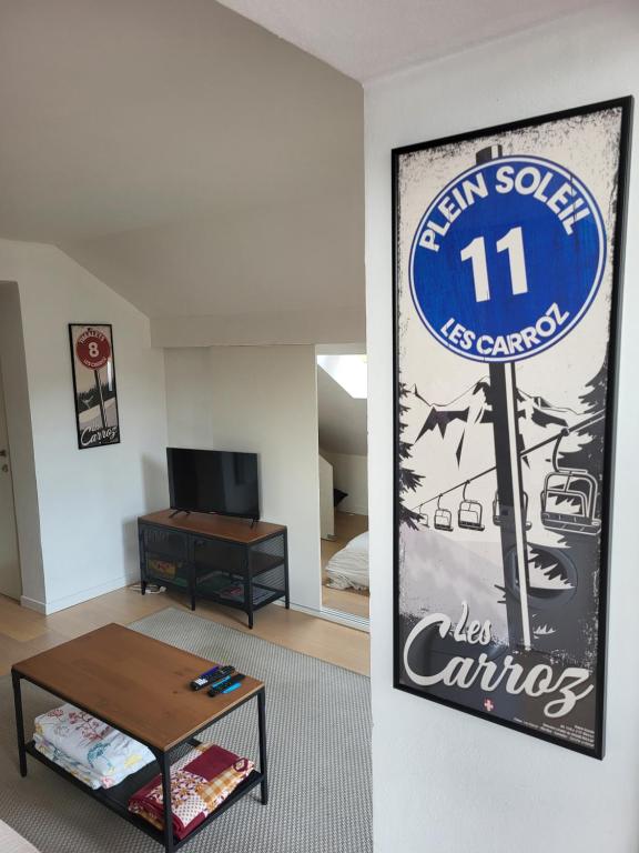 una sala de estar con un cartel en la pared en Duplex les Myrtilles LES CARROZ centre station, en Les Carroz d'Araches