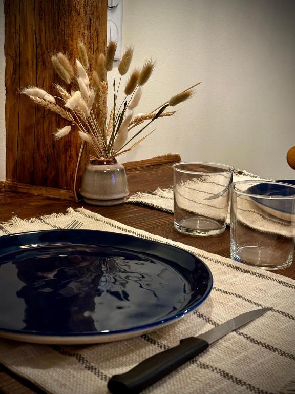 a table with a blue plate and two glasses on it at Studio centre historique - climatisé in Pézenas