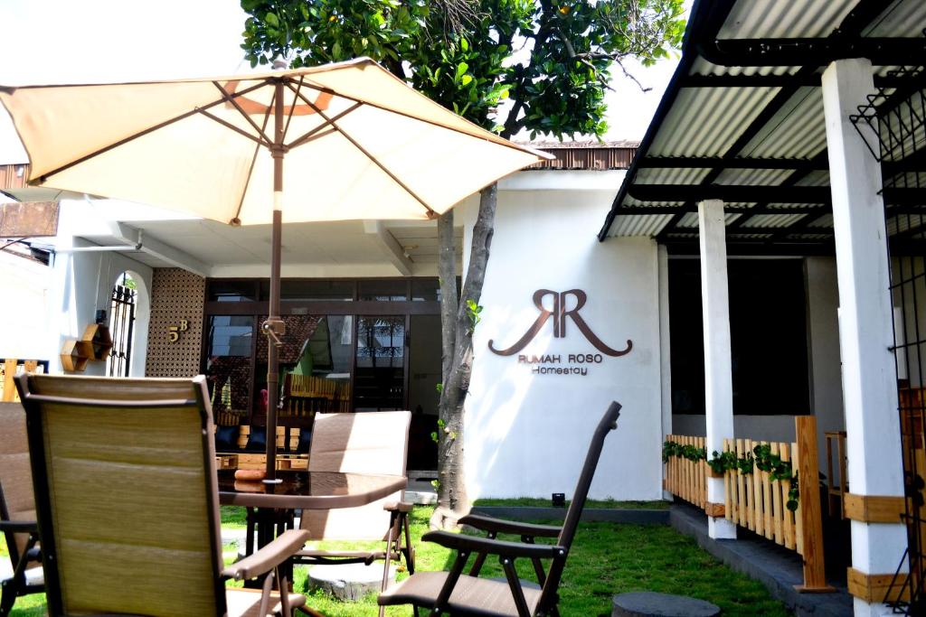 a table and chairs with an umbrella in front of a building at Rumah Roso Homestay in Yogyakarta