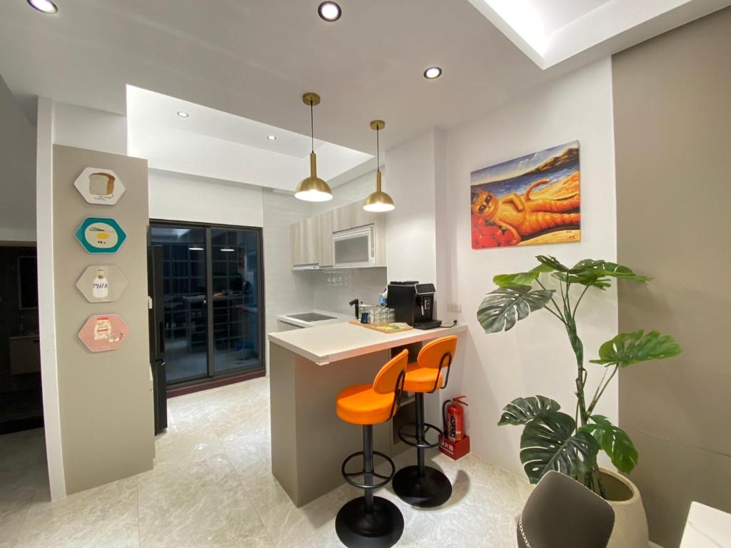a kitchen with orange stools and a counter in a room at MUMU Villa in Hengchun