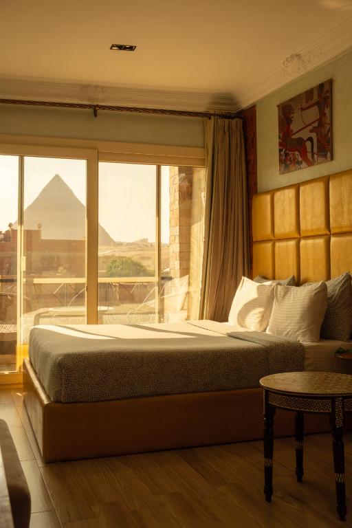 a bedroom with a bed with a view of the pyramids at Jimmy Pyramids Hotel in Cairo