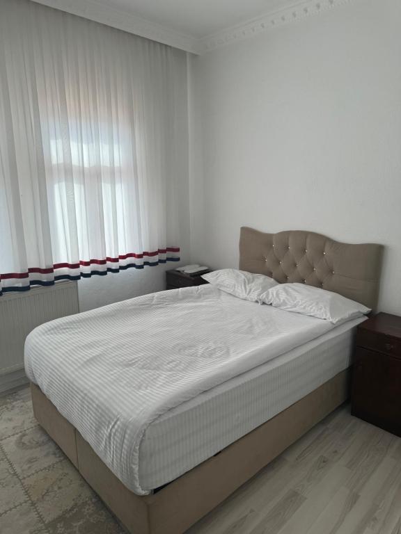 a bedroom with a large bed with white sheets at Gümüş Hotel in Ortahisar