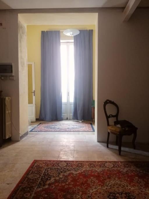 a hallway with a chair and a window with blue curtains at Appartamento Teatro Duse in Bergamo