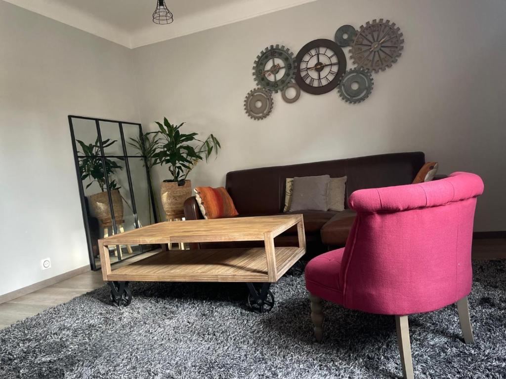 - un salon avec un canapé et une chaise rose dans l'établissement Appartement Le Raincy, à Le Raincy