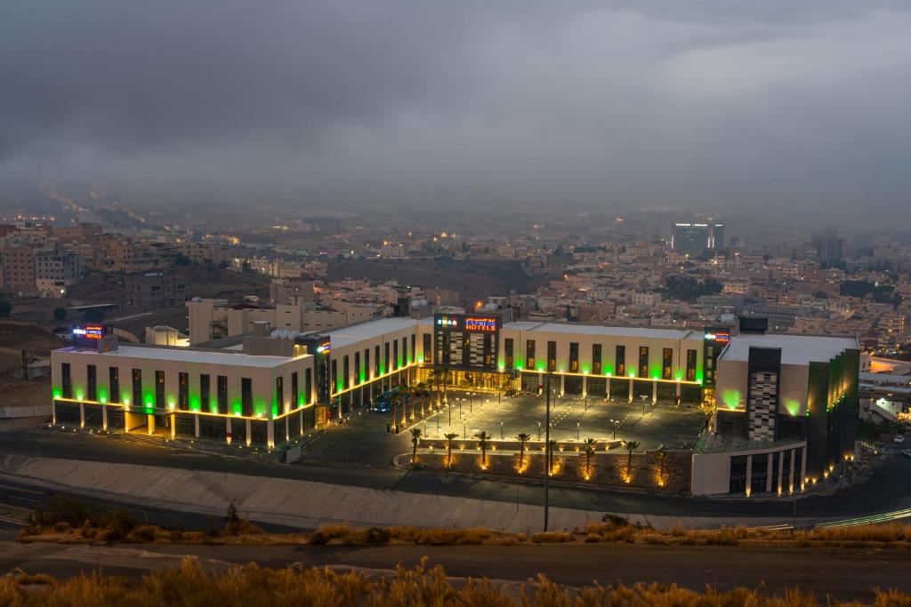 a building with green lights in a city at night at Ewaa Express Hotel - Abha in Abha