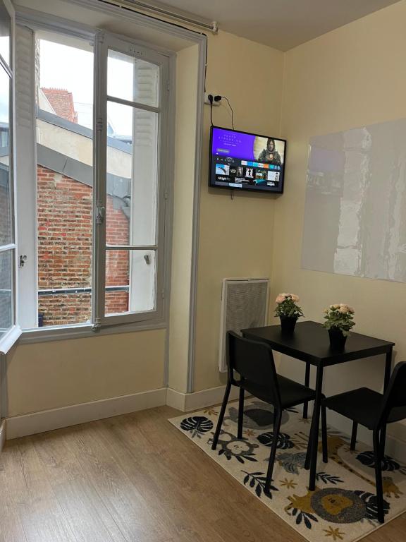 une salle à manger avec une table et une télévision au mur dans l'établissement Charmant studio spacieux paris, à Paris