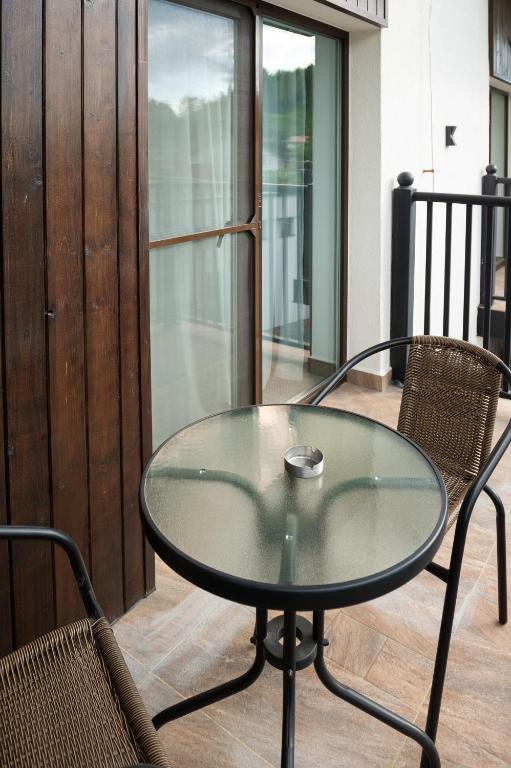 a glass table and two chairs on a balcony at Complex Pescăresc Gura Repezii Borșa in Borşa