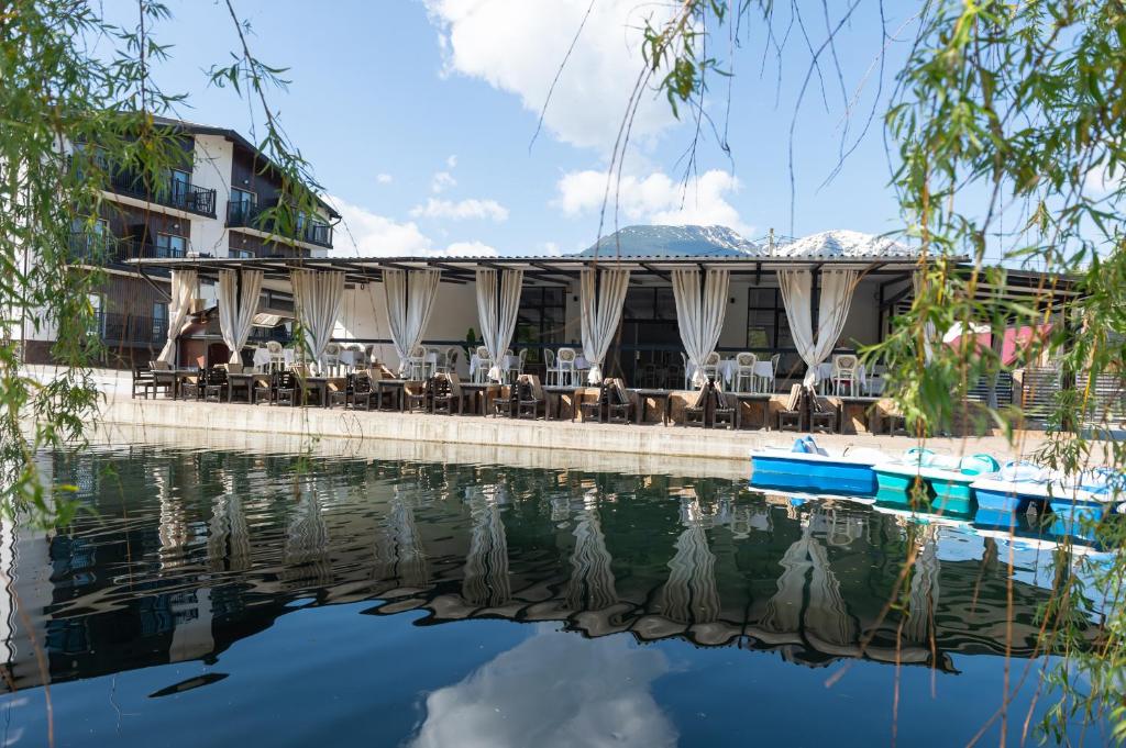 a hotel with tables and chairs next to a body of water at Complex Pescăresc Gura Repezii Borșa in Borşa