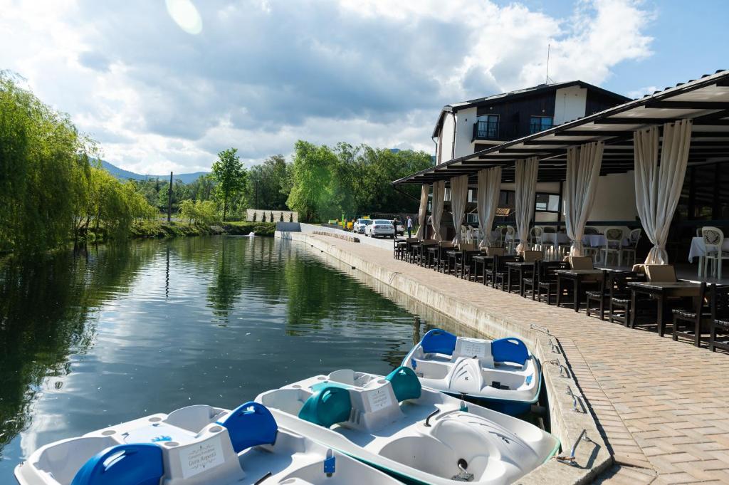two boats are docked at a restaurant on a river at Complex Pescăresc Gura Repezii Borșa in Borşa