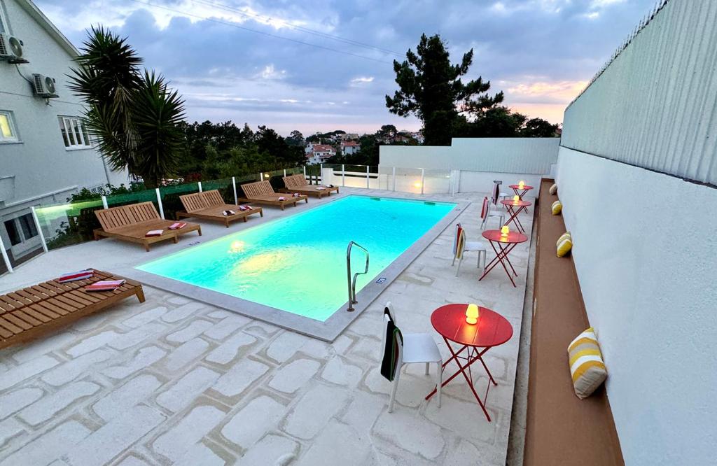 Una vista aérea de una piscina con sillas y mesas. en Boutique Hotel - O House Ericeira Hills, en Ericeira
