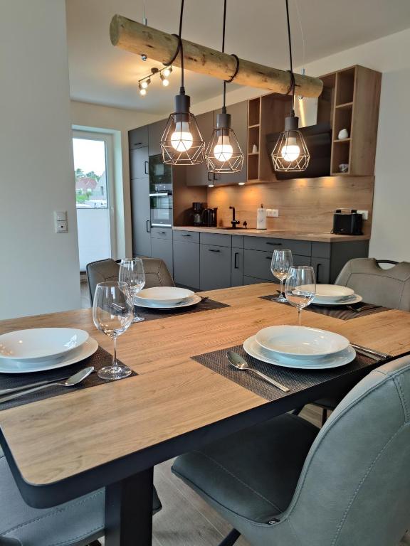 a wooden table with plates and wine glasses on it at Haus Albatros EG - Exklusive Fewo für 4 Personen in Dangast