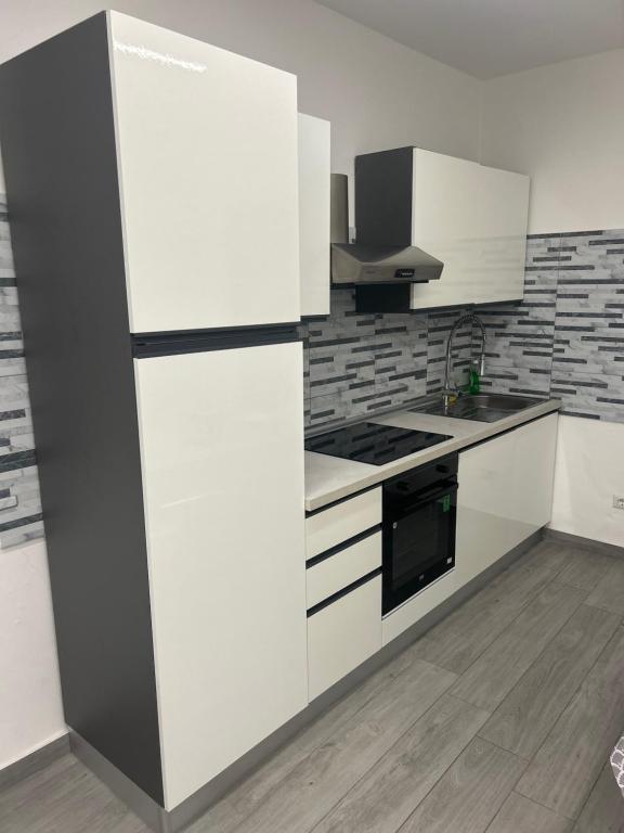 a kitchen with white cabinets and a black and white refrigerator at Appartamento Tortona in Tortona