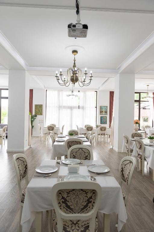 a dining room with white tables and chairs and a chandelier at Complex Pescăresc Gura Repezii Borșa in Borşa