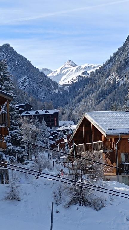 un lodge dans la neige avec des montagnes en arrière-plan dans l'établissement Location semaine 7 nuits du samedi au samedi Studio 20m2 cozy 4pers au pied d une piste bleu accès remontés, à Valfréjus