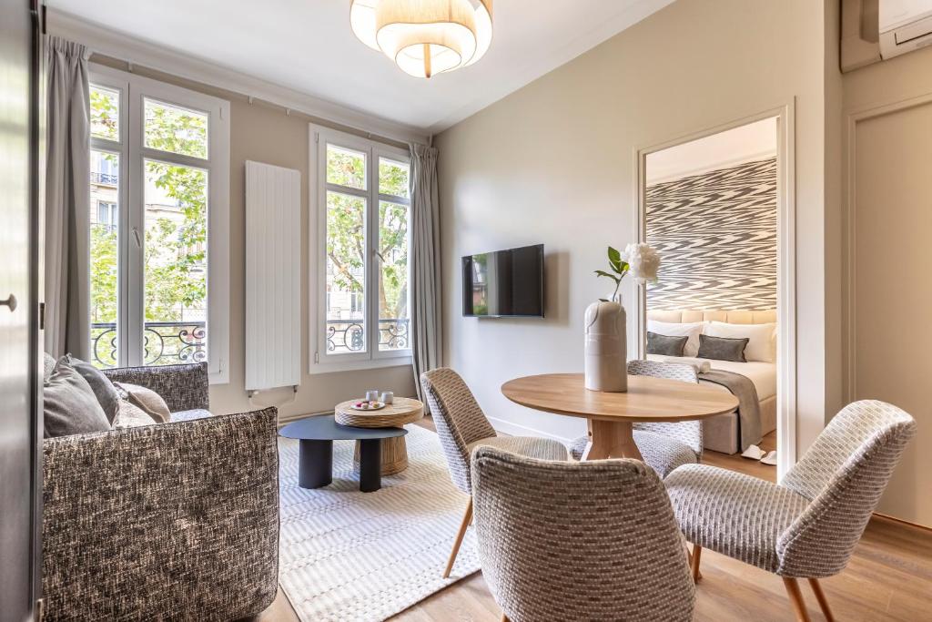Una sala de estar con una mesa y sillas y un sofá. en Sweett - Villiers, en París