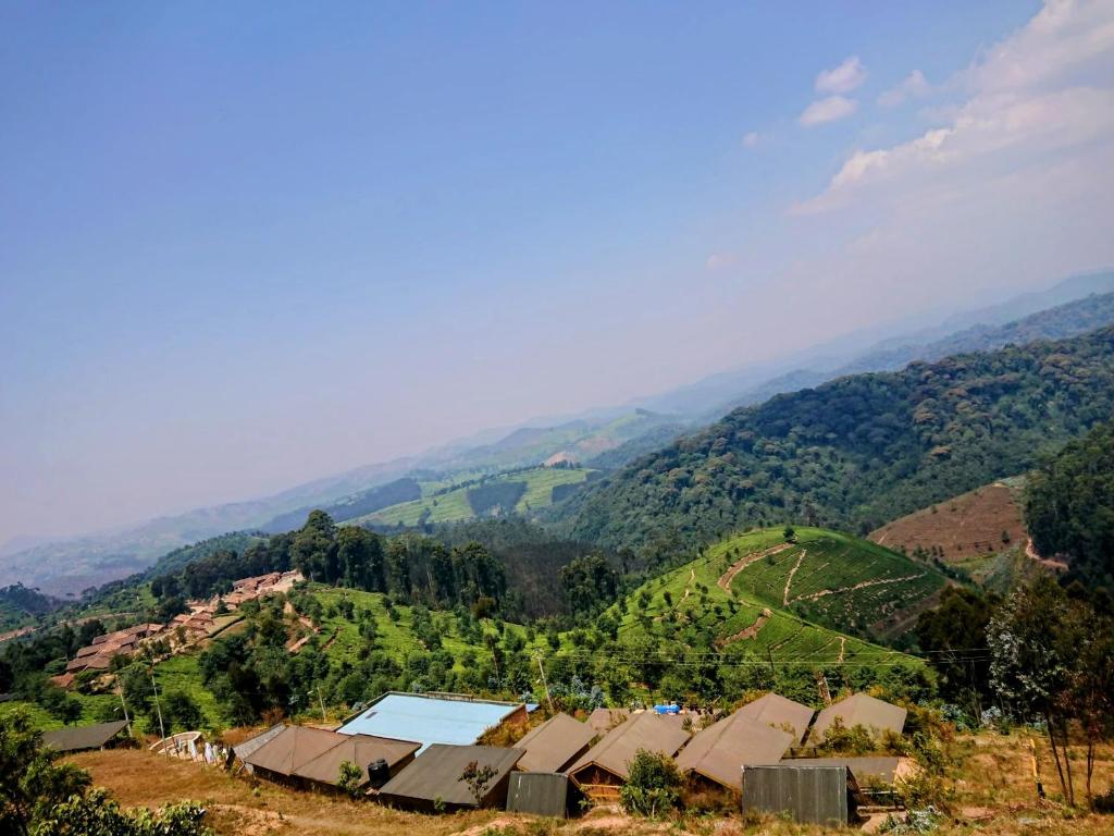 a village on a hill with mountains in the background at NYUNGWE VILLAGE in Kitabi