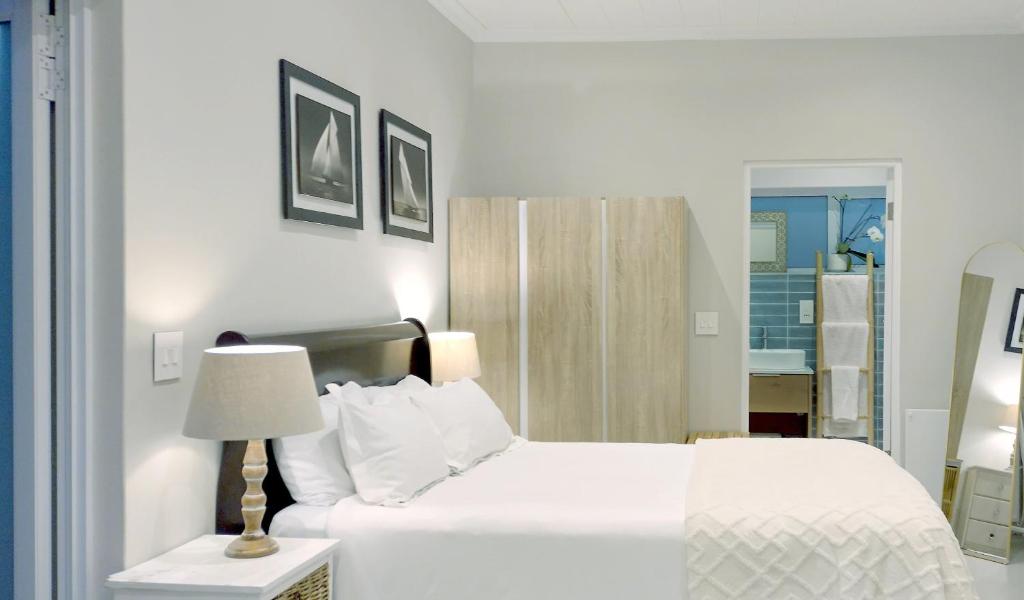 - une chambre blanche avec un lit et une lampe dans l'établissement Sea Breeze Cottage, au Cap