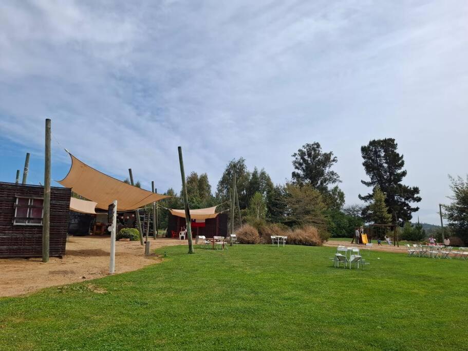 a park with a tent and picnic tables in the grass at Parcela Lago Rapel in Lago Rapel