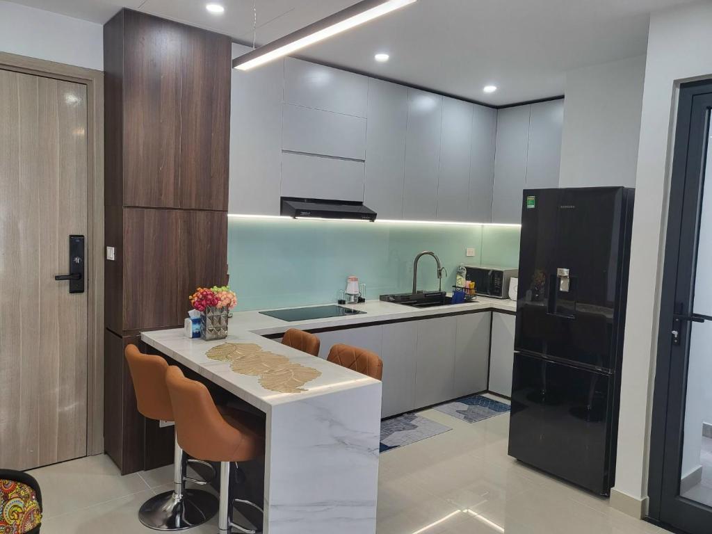 a kitchen with a table and a black refrigerator at T- Plus Apartment - Căn hộ 2 PN view hồ bơi in Thôn Văn Dương