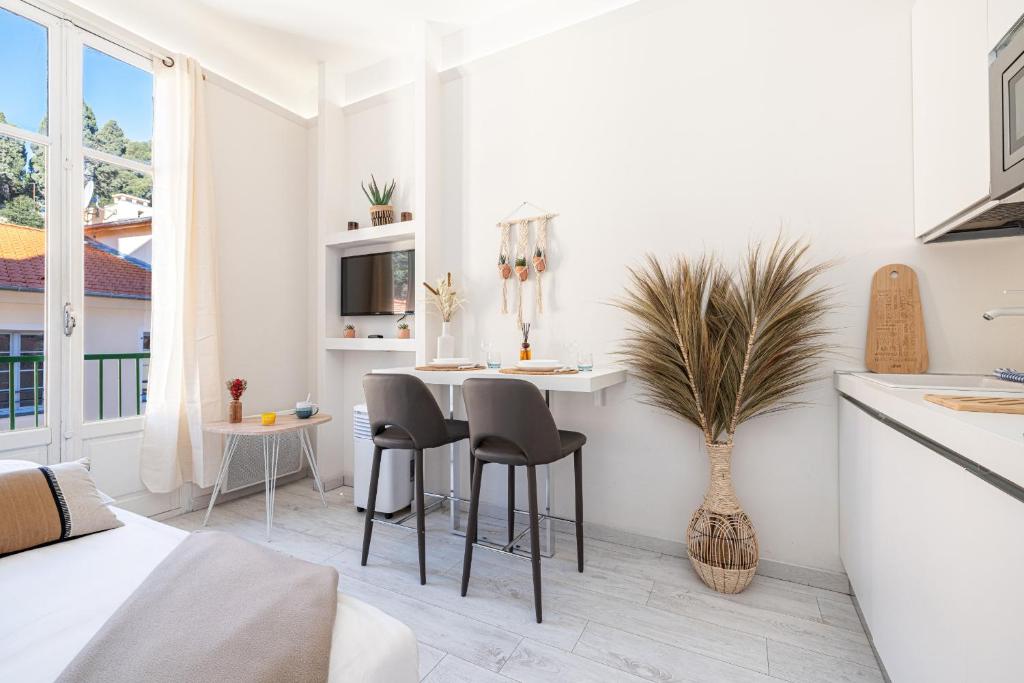 une cuisine blanche avec une table et des chaises dans l'établissement 1 GAUTIER 501 - Studio boheme - Quartier du port, à Nice