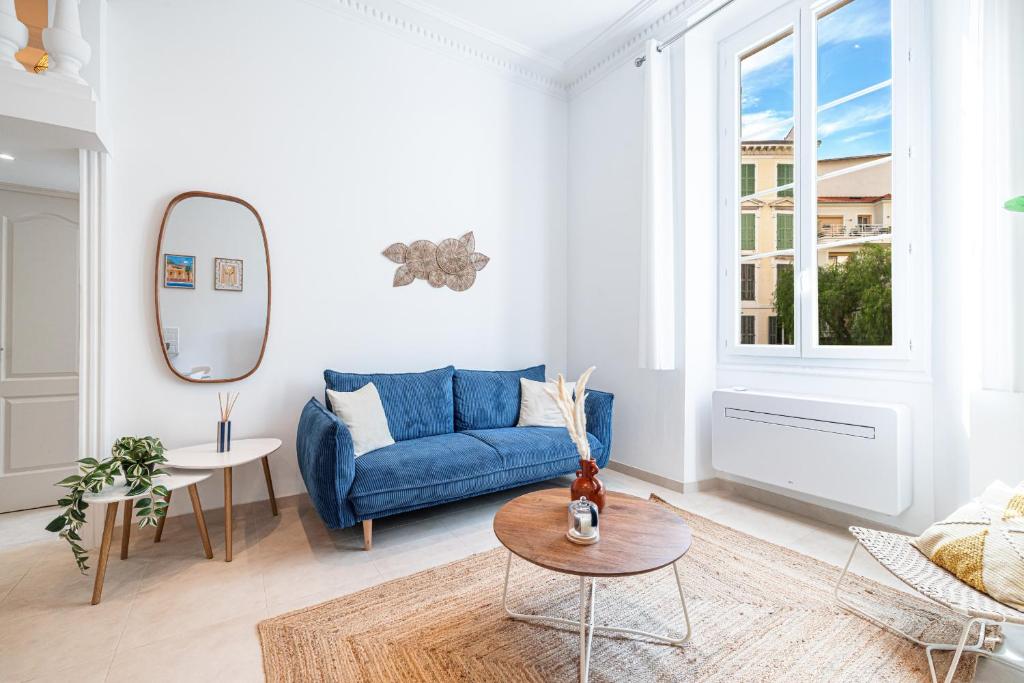 un salon avec un canapé bleu et un miroir dans l'établissement 1 LONGCHAMP - Joli appartement - Carre d Or - Climatise, à Nice