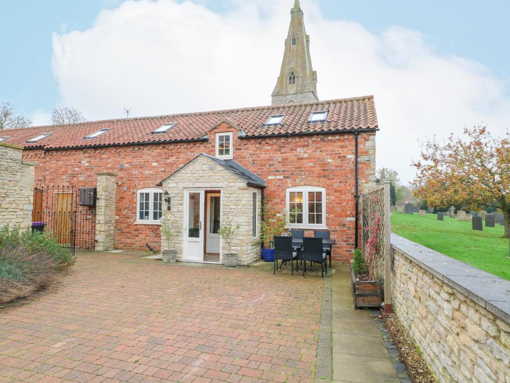 a brick church with a steeple on top of it at Church Barn in Grantham