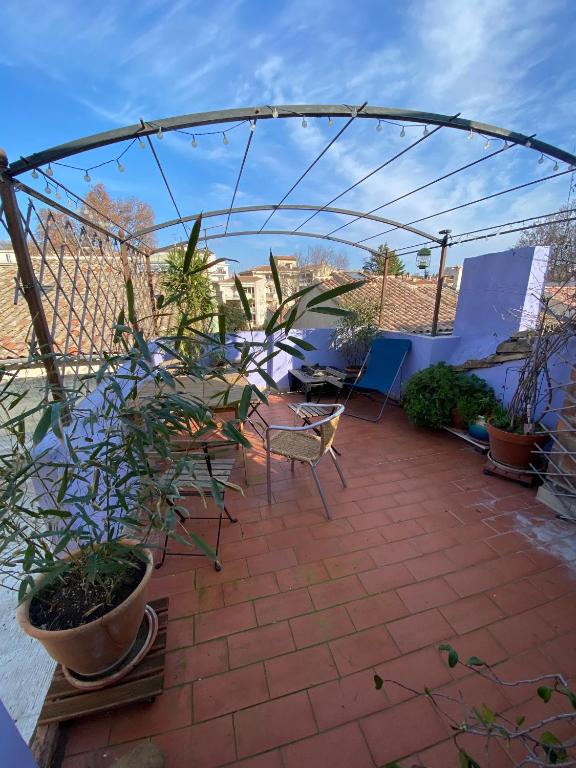 une tonnelle avec des chaises et des plantes en pot sur une terrasse dans l'établissement Pretty house in the heart of Avignon, à Avignon