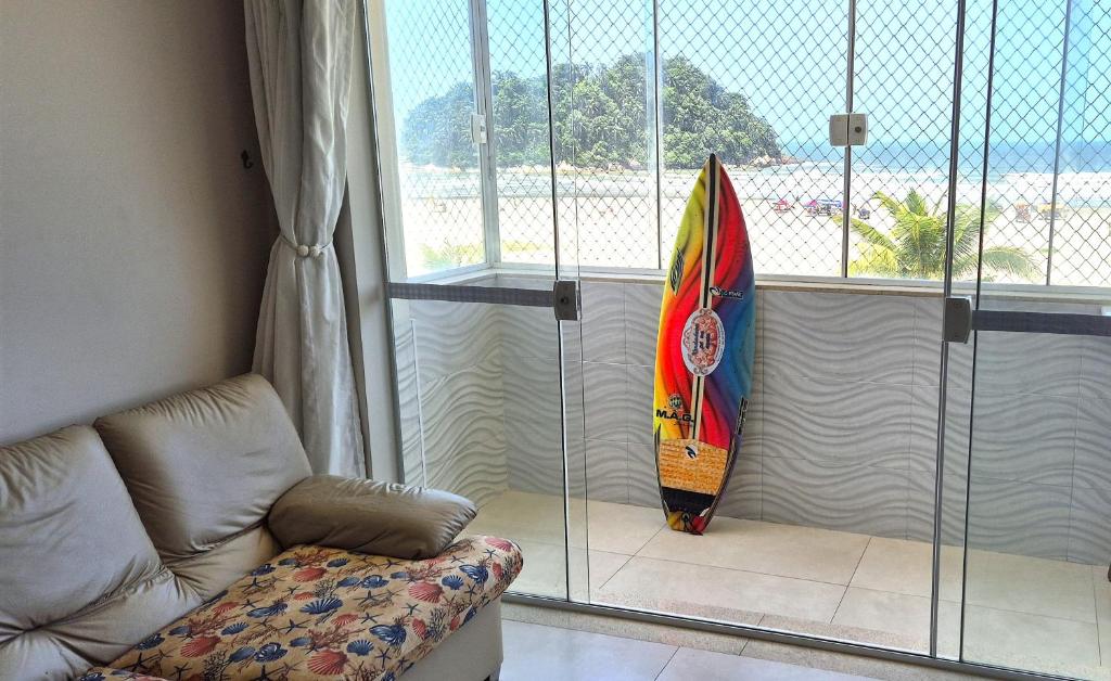 a surfboard leaning up against a window with a couch at Verdadeiro pé na areia TOP in Santos