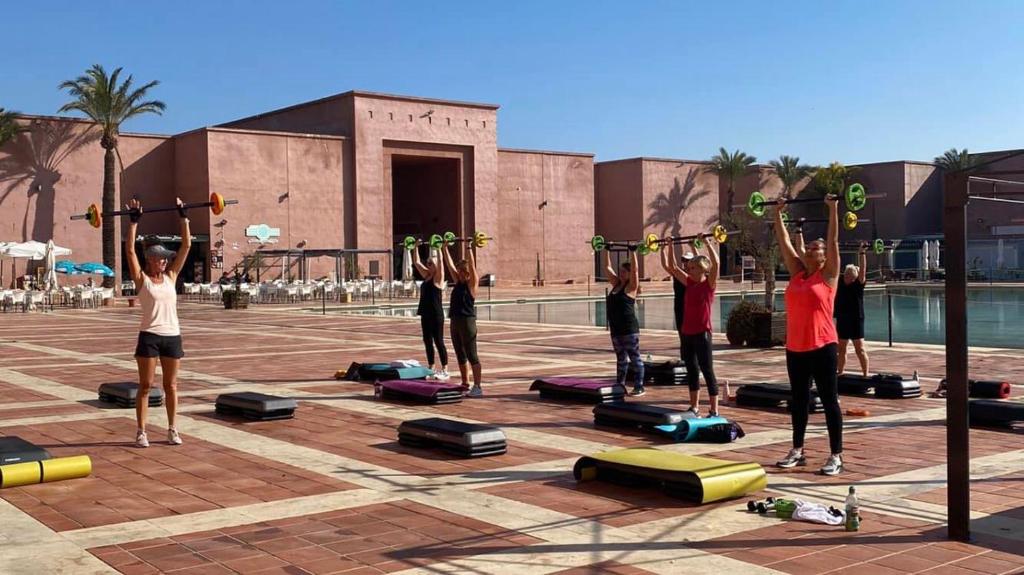 un gruppo di persone che fa una posa yoga di fronte alla piscina di Casa Diana Golf a Murcia