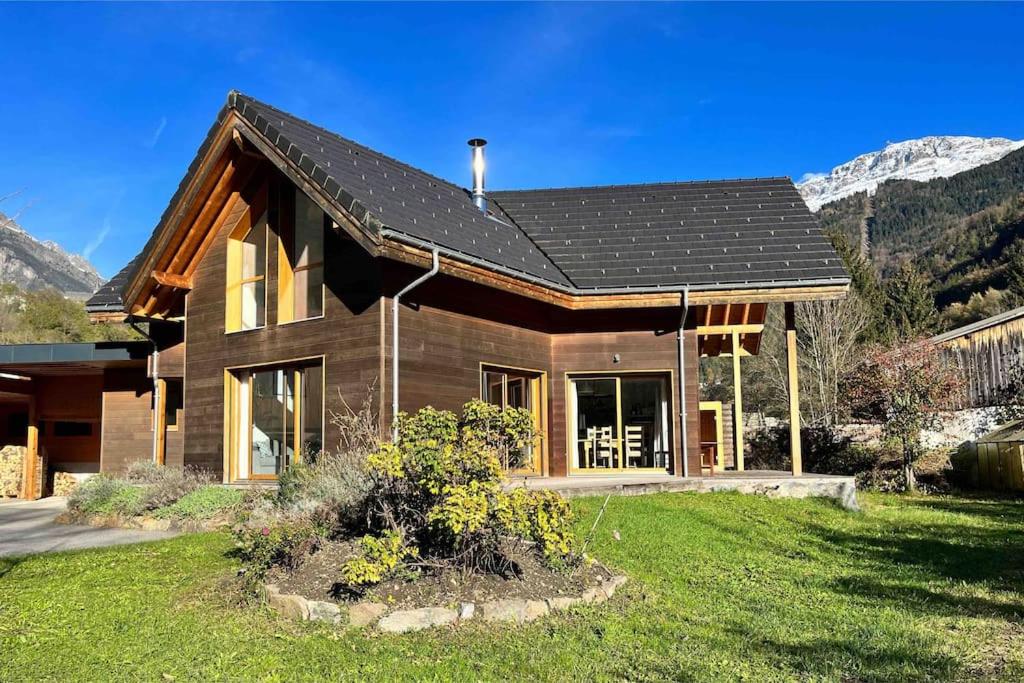 une maison en bois avec une montagne en arrière-plan dans l'établissement Maison Blanche, Impressive Chalet, Allemond, Bike, Ski, Hike, à Allemont