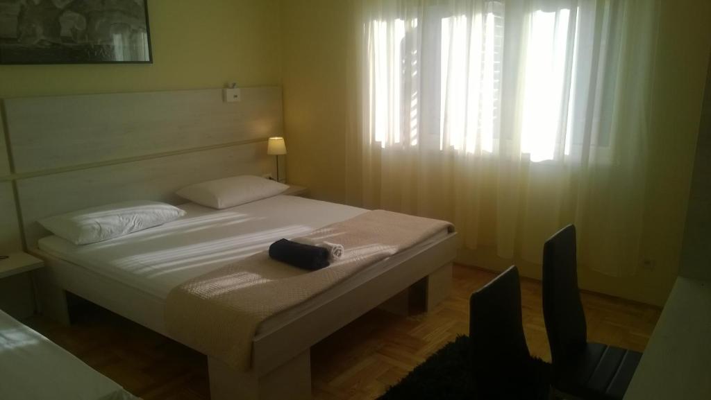 a bedroom with a white bed with a black bag on it at Rooms & Apartments Blue Beach in Vodice