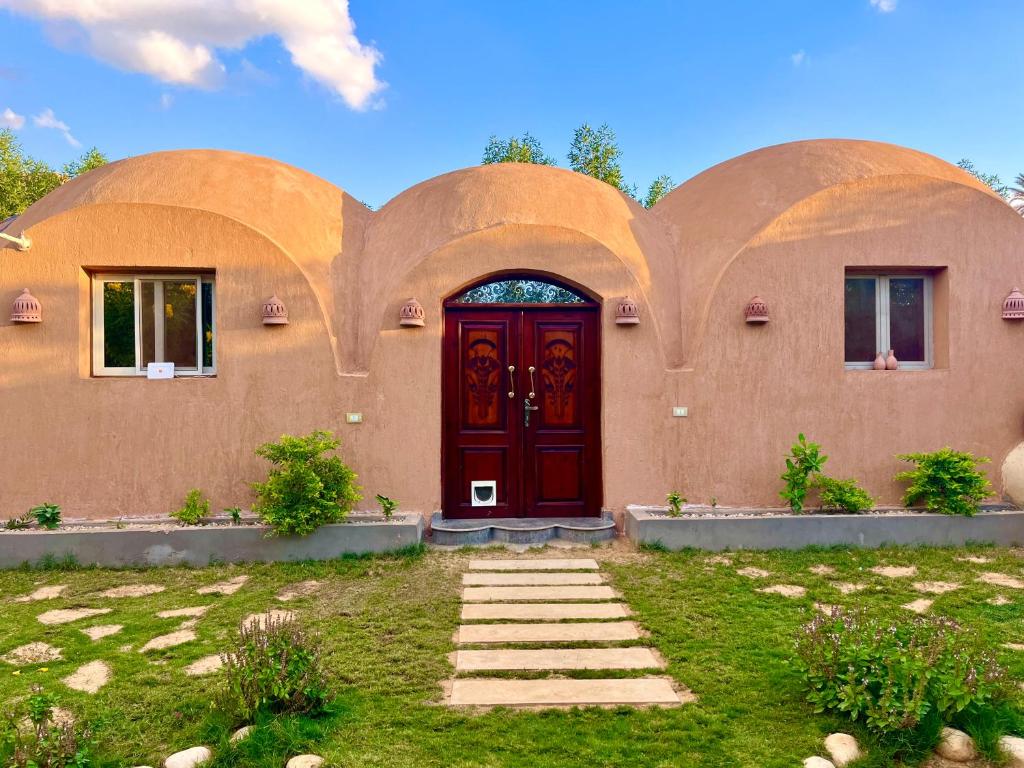 a home with a red door and a yard at Sahure Pyramid View Inn in Cairo