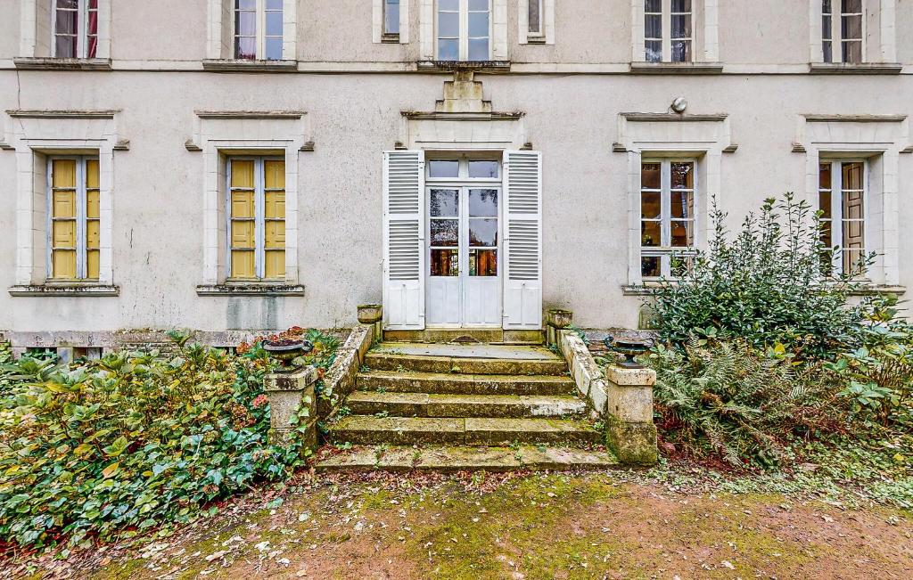 - un bâtiment ancien avec des escaliers menant à une porte dans l'établissement Maison Saint-Lyphard, à Saint-Lyphard