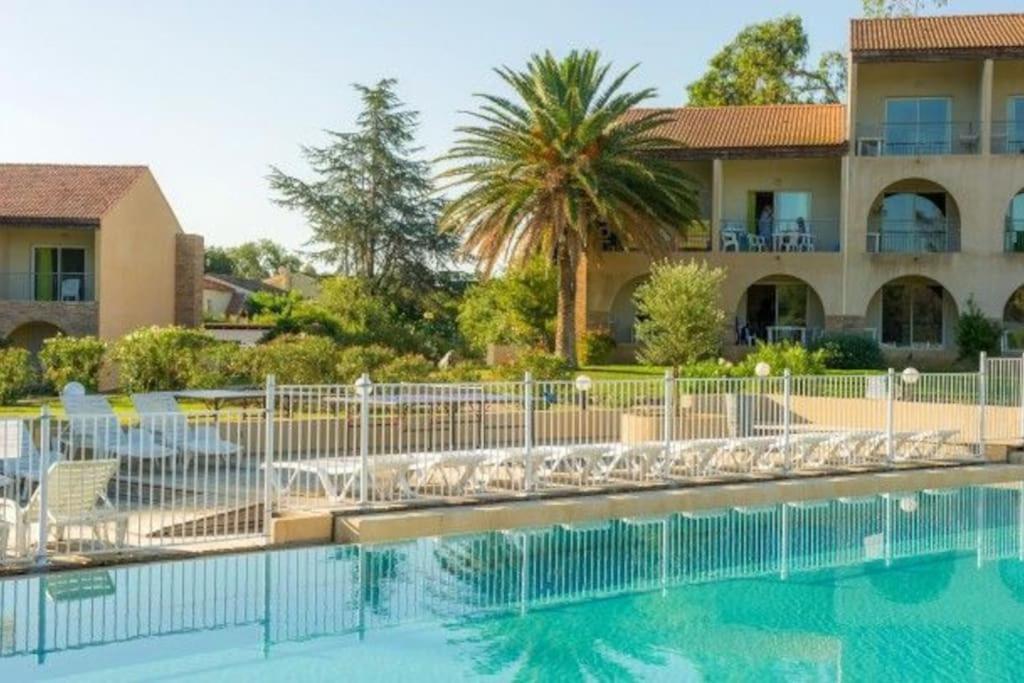une piscine avec des chaises et un bâtiment dans l'établissement Appartement avec piscine à 2 pas de la plage, à Linguizzetta