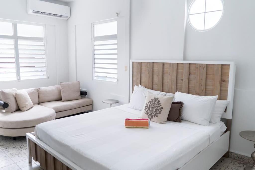 una camera da letto bianca con un letto grande e un divano di 8 Atlantic Place by Stay with Bear a San Juan