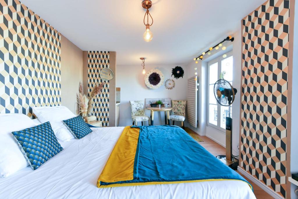 - une chambre dotée d'un grand lit avec des draps bleus et jaunes dans l'établissement L'ILLUSIONISTE studio dans le Suquet avec aperçu mer, à Cannes