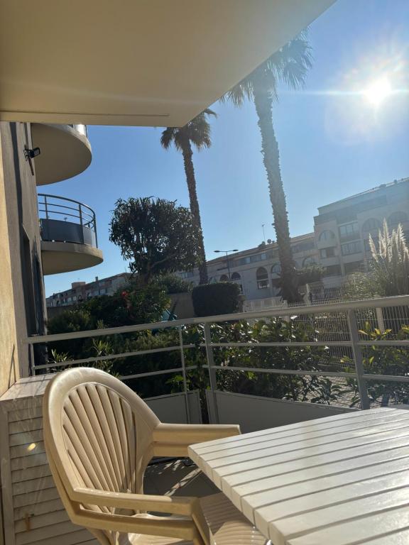 d'une table et de chaises sur un balcon avec des palmiers. dans l'établissement Logement cosy en bord de mer et étang, à Sète