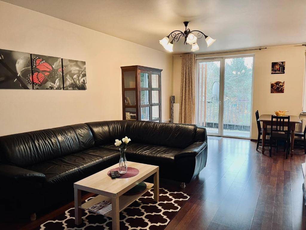レギオノボにあるLegionowo 3 pokoje gen Boleslawa Roiのリビングルーム(黒い革張りのソファ、テーブル付)