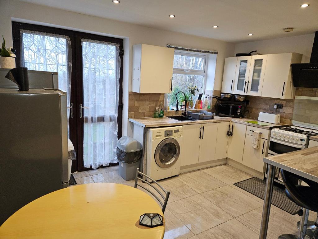 a kitchen with white cabinets and a washer and dryer at Monyhull Homestay - near City centre Kingsheath NIA NEC BHX in Birmingham