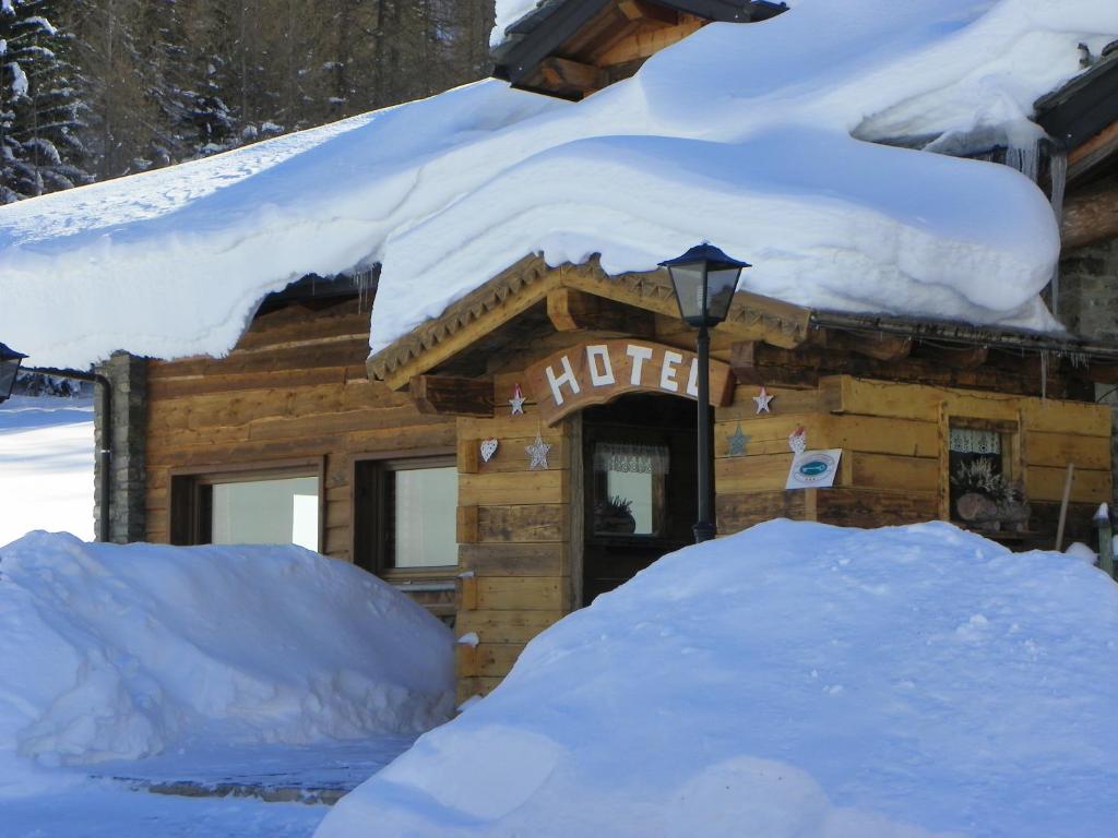 ein schneebedecktes Blockhaus mit einem Schild darauf in der Unterkunft Hotel Les Granges in La Thuile