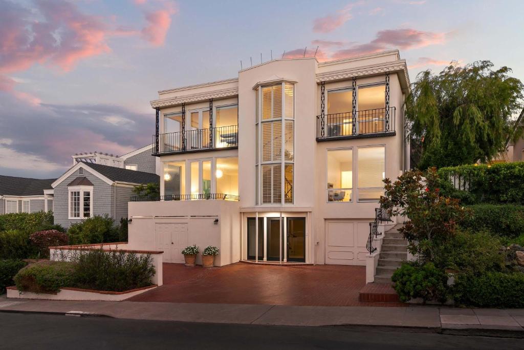 Cette grande maison blanche possède de nombreuses fenêtres. dans l'établissement Sea Serenity Coastline Views and Pool, à San Diego