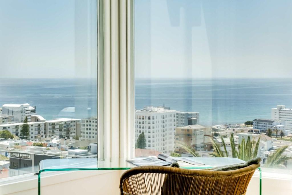 a glass table and a chair in front of a window at Ocean Vue in Cape Town
