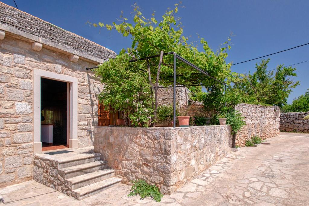 a stone house with a stone wall and stairs at Holiday Home Rudina in Stari Grad