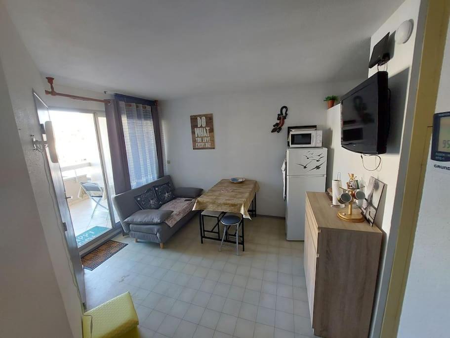 Il comprend une petite cuisine et un salon avec un canapé et une table. dans l'établissement Appartement à 2 pas de la mer, à Canet
