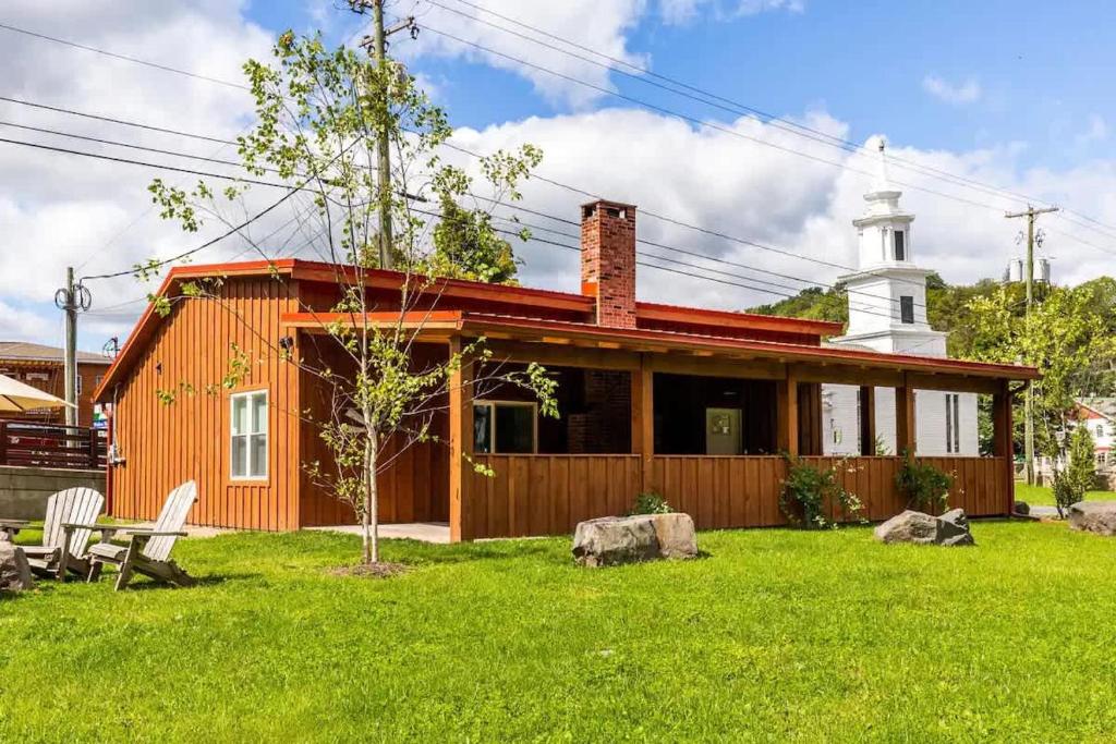 a house with a green yard with a building at Mountain Cabin with Scenic Views and Hot Tub in Windham