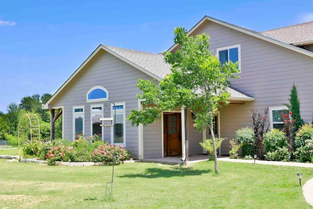 a house with a tree in the front yard at Hailey's Cottage on Small Farm-16 minutes to Silos in Bellmead