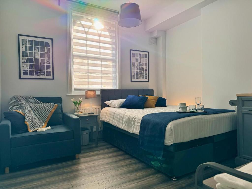 a bedroom with a bed and a blue chair at Camden Luxury Studio Flats and En-Suit Rooms in London