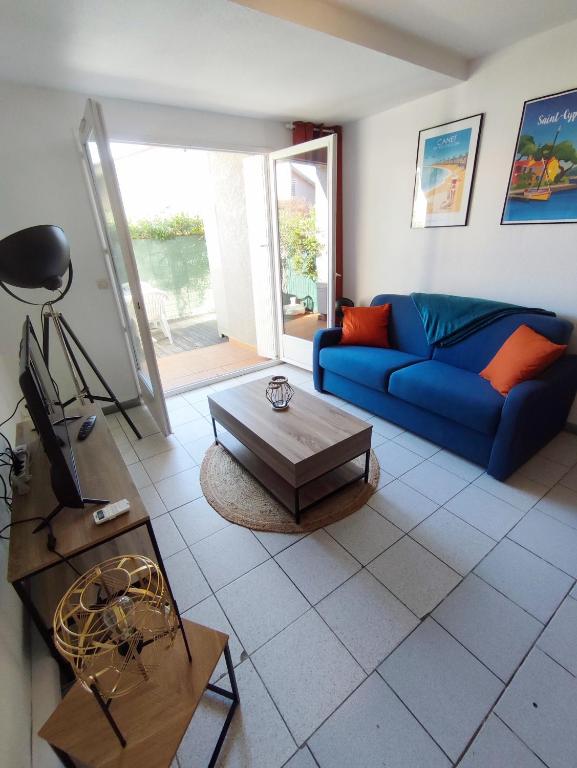 un salon avec un canapé bleu et une table dans l'établissement Appartement du port, à Saint-Cyprien